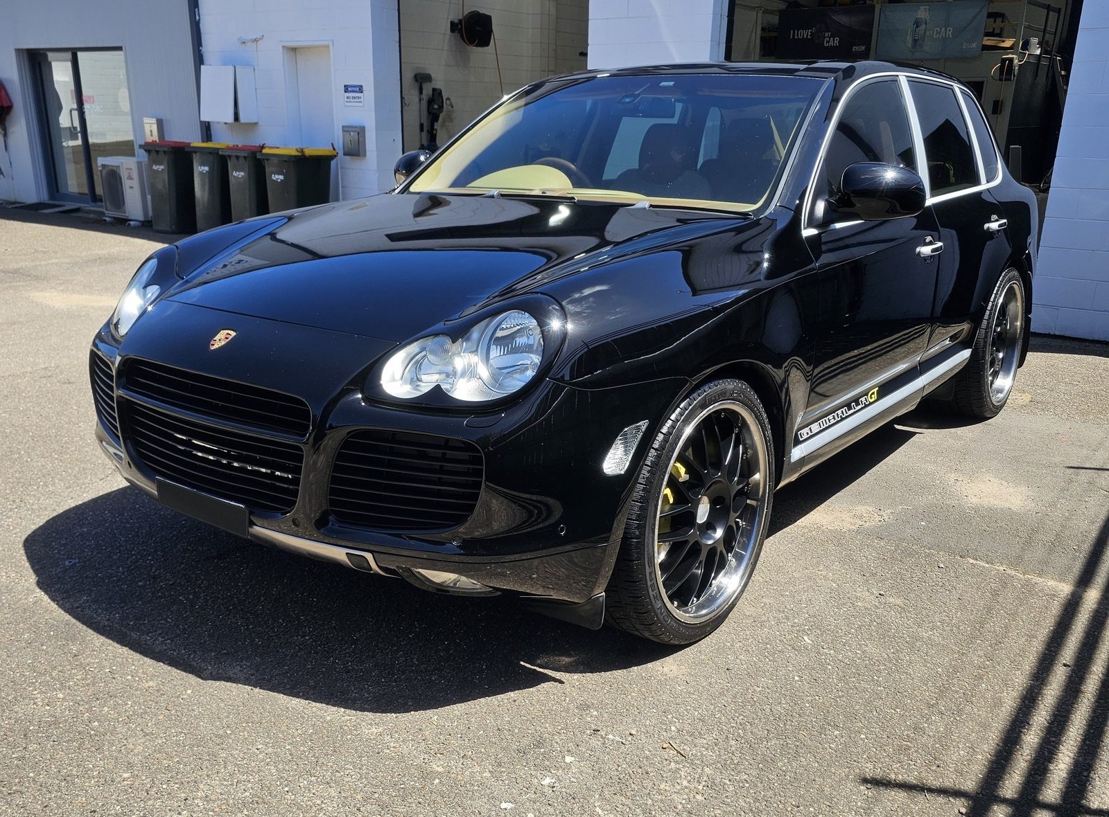 Black Porsche Cayenne 955 in bright outdoor light with strong gloss and reflections after correction.